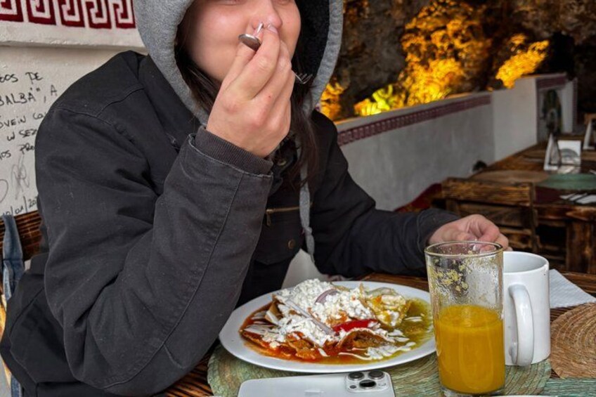 Une personne est assise à une table, devant un plat, et a une boisson à portée de main. 3