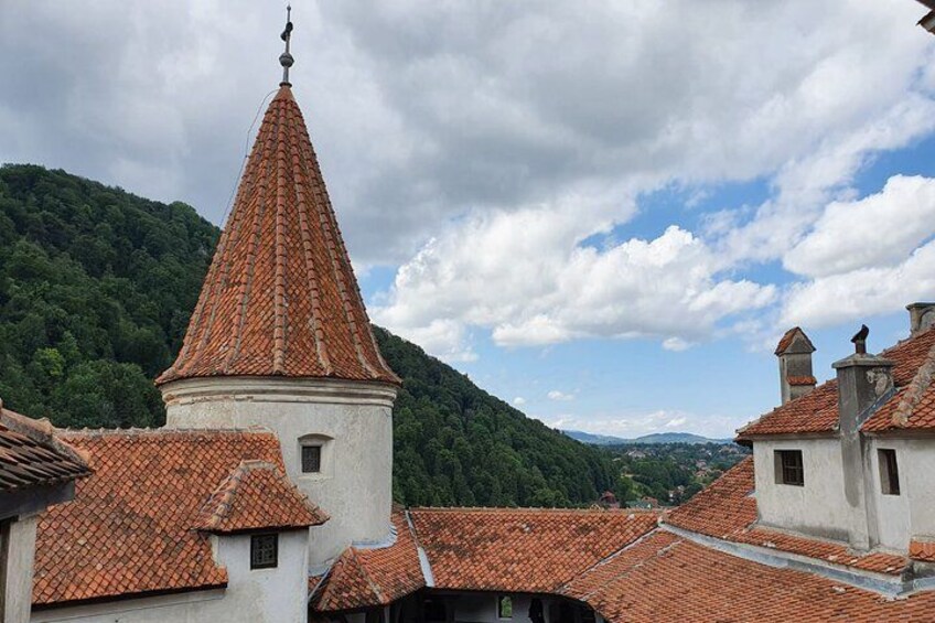 A village with red-tiled roofs, a church with a tall bell tower, and green hills in the background. 2