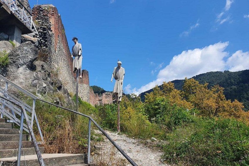 A historical site with statues, a staircase, and a mountainous backdrop. 4