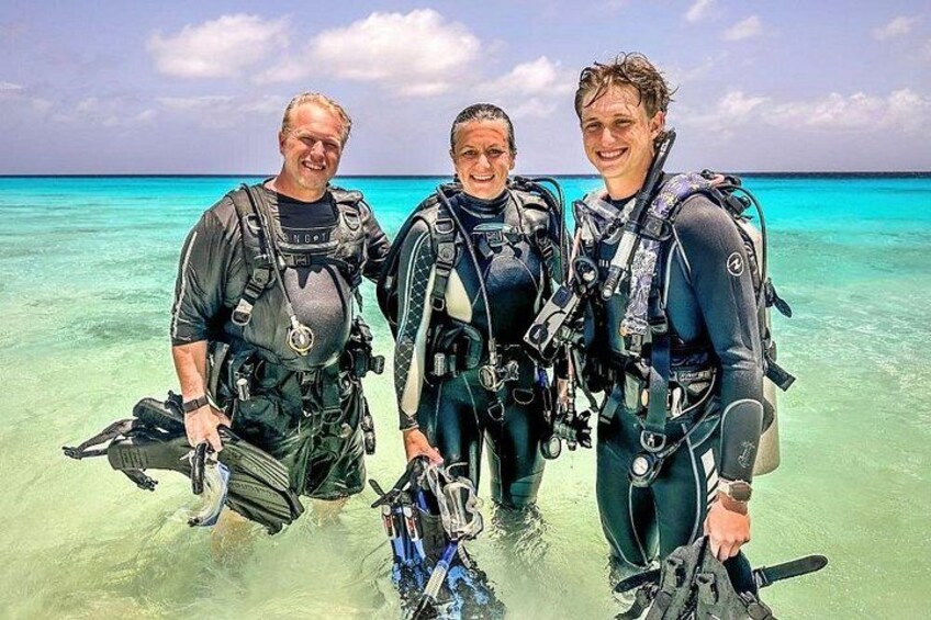 Three people in scuba diving gear standing in shallow water. 5