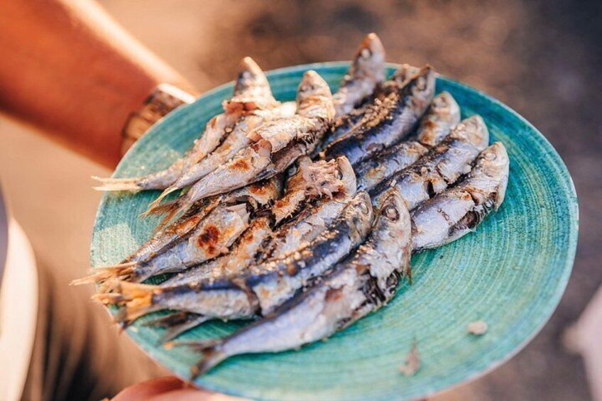 Une personne tenant une assiette bleue sur laquelle se trouve du poisson grillé. 4