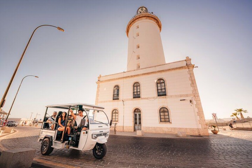 Un coche blanco con pasajeros cerca de un edificio histórico con una torre alta. 1
