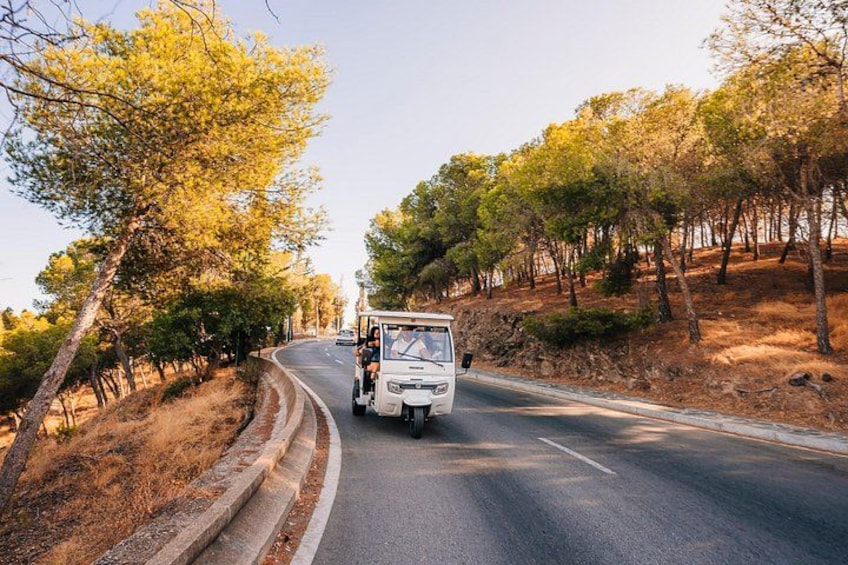 A white vehicle on a winding road surrounded by trees. 3