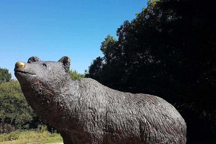 Una gran estatua de oso en un entorno natural con árboles al fondo. 2
