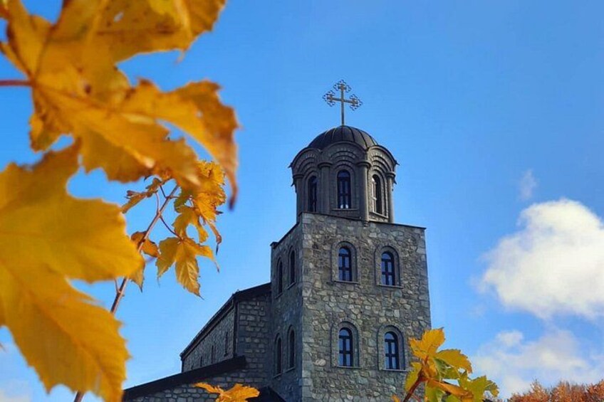 En kyrka byggd av sten, med ett klocktorn och en vindflöjel. 2