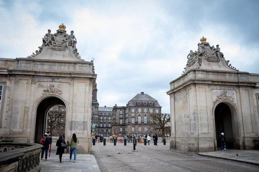 A historic building with ornate architecture, a large arched entrance, and a crowd of people in the foreground. 3