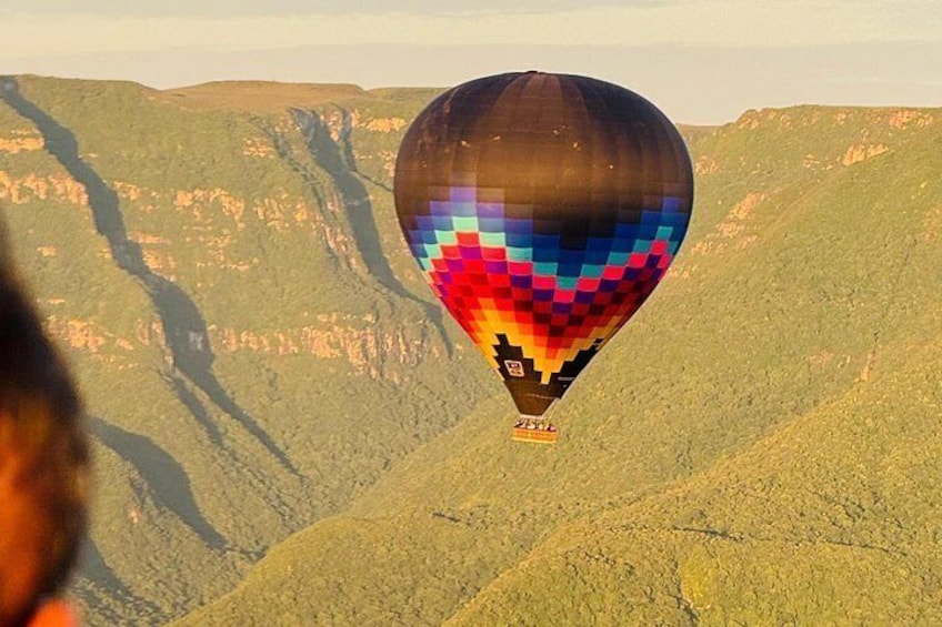 Een luchtballon met een kleurrijk patroon vliegt boven een kloof. 5