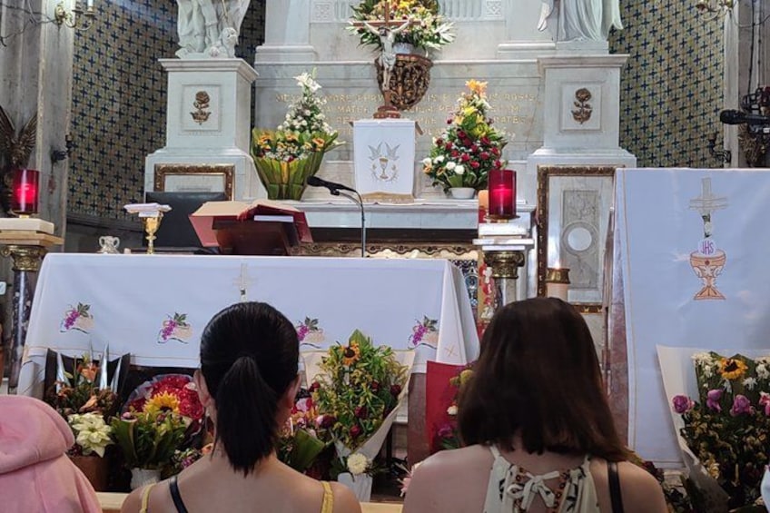 A church interior with a statue, altar, flowers, and religious icons. 5