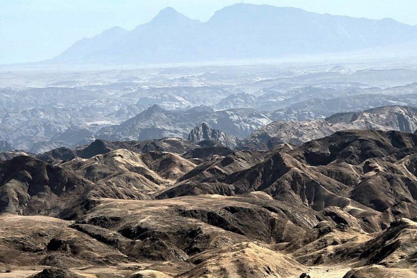 Un paisaje montañoso y accidentado con terreno rocoso y montañas distantes. 3