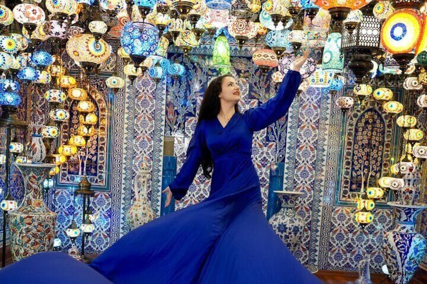 Una persona con vestido azul de pie frente a un muro decorado con faroles coloridos y ornamentados. 5