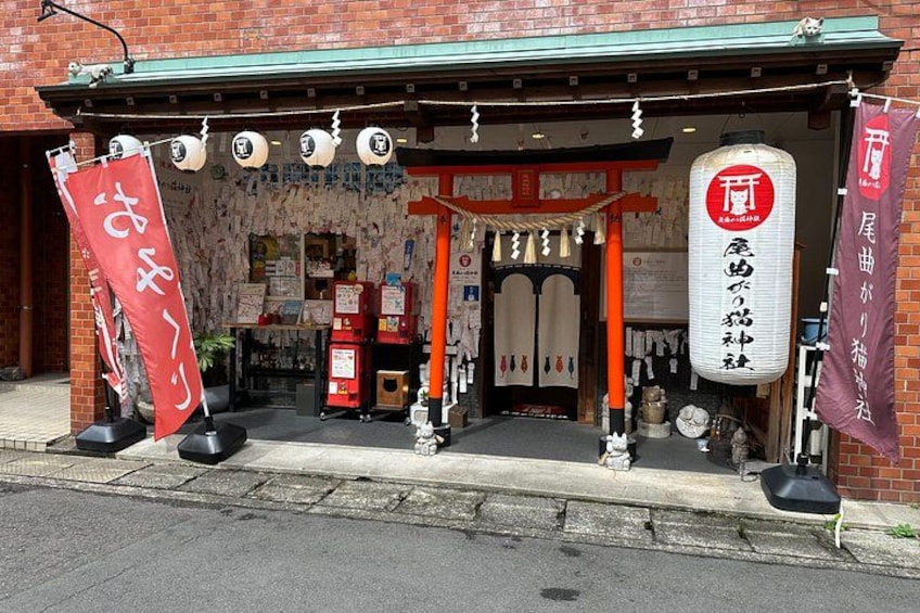 Ein traditionelles japanisches Gebäude mit roter und weißer Fassade, einem hölzernen Eingang und Fahnen mit japanischen Schriftzeichen. 3