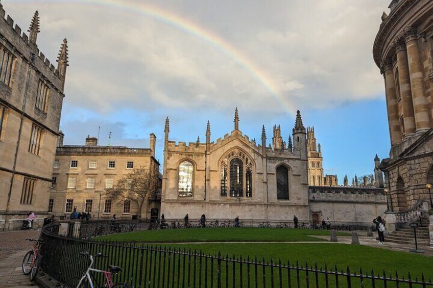 A historic building with a large arched entrance and a rainbow in the sky. 5