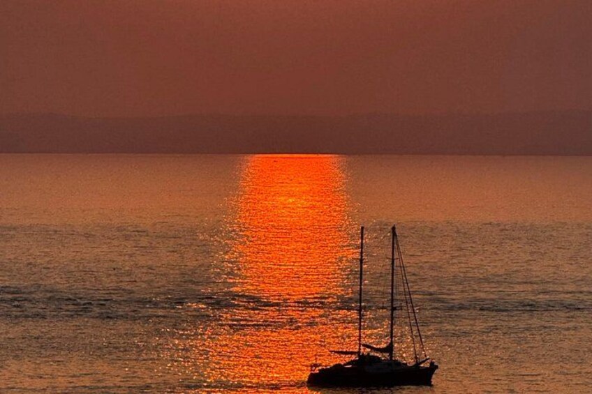 Un atardecer sobre un mar tranquilo con un velero. 4