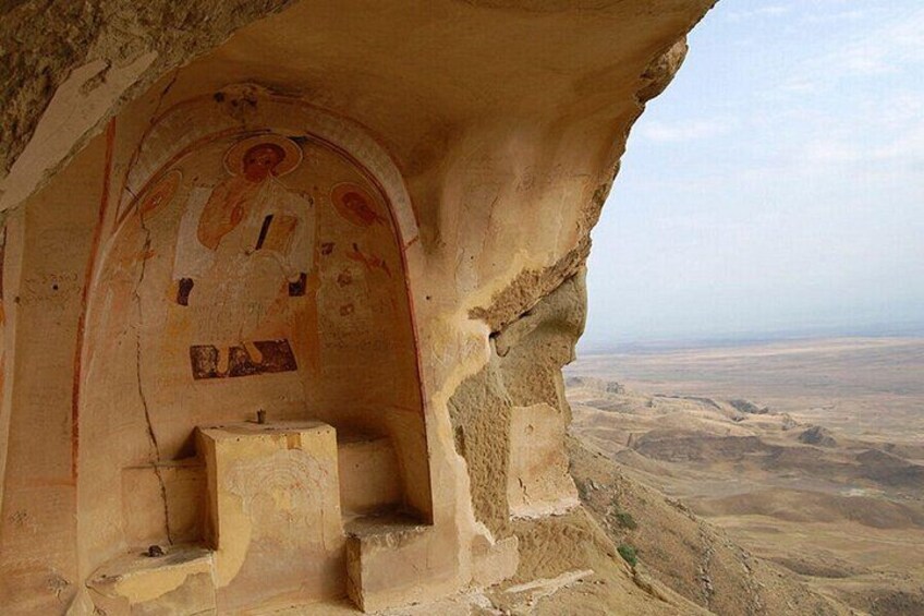 A cave with ancient frescoes and a view of a desert landscape. 3