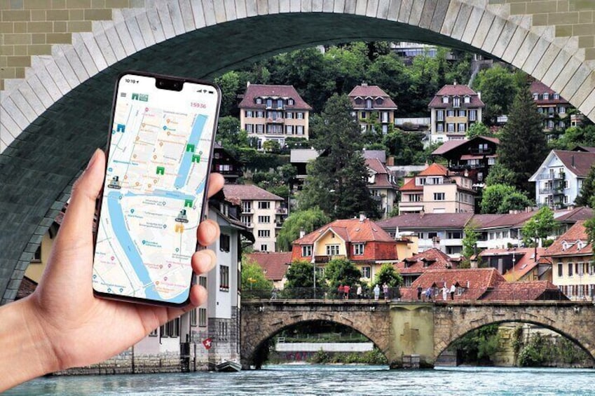 Una mano che tiene uno smartphone con una mappa sullo schermo, sullo sfondo un ponte e degli edifici. 1