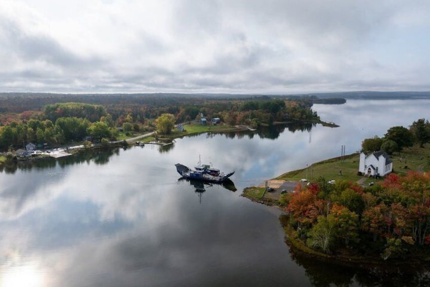 A calm lake with a boat, surrounded by autumn-colored trees and a white building. 3