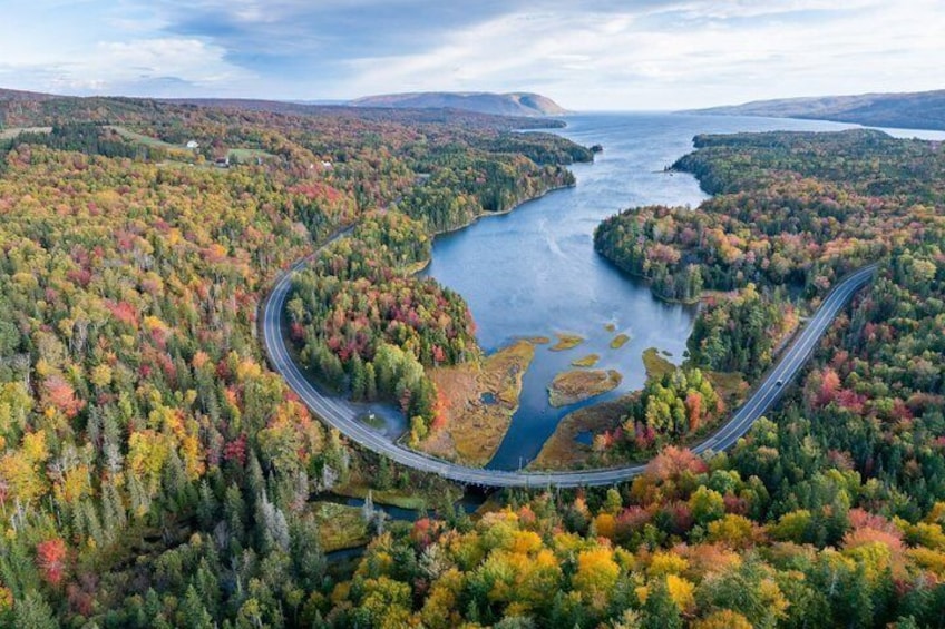 A winding road through a forested area with a lake. 2