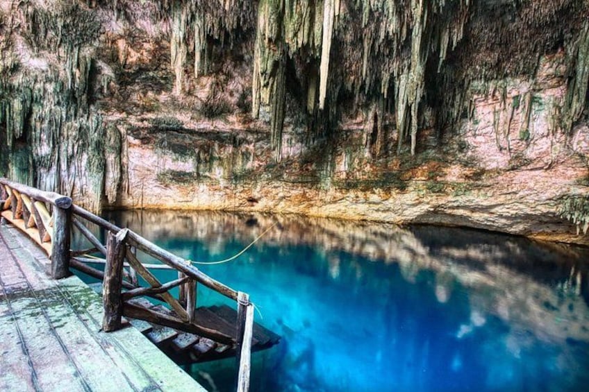 Un puente de madera sobre una piscina azul cristalina con rocas cubiertas de musgo y musgo colgante. 4