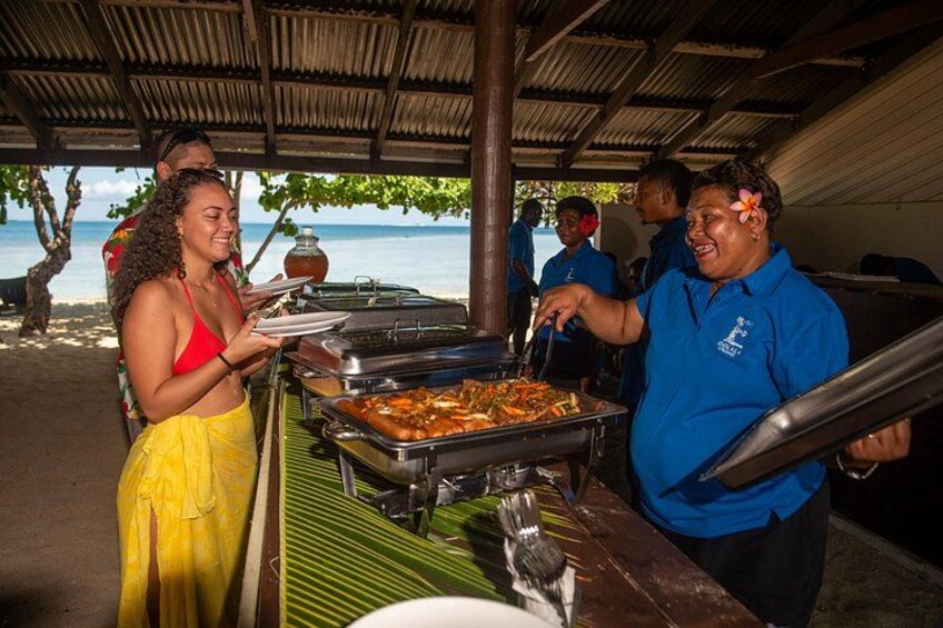 A buffet setup with food trays and people serving. 5
