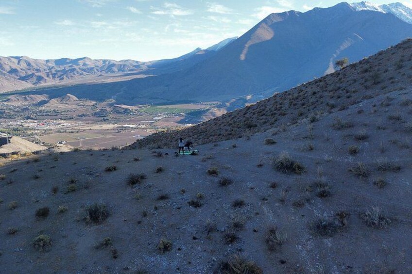 Paesaggio collinare con vegetazione rada e una vista in lontananza di una valle e montagne. 4