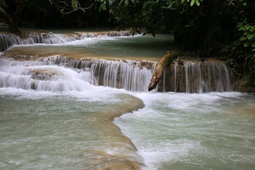 A multi-tiered waterfall with water cascading over rocks in a forested area. 4
