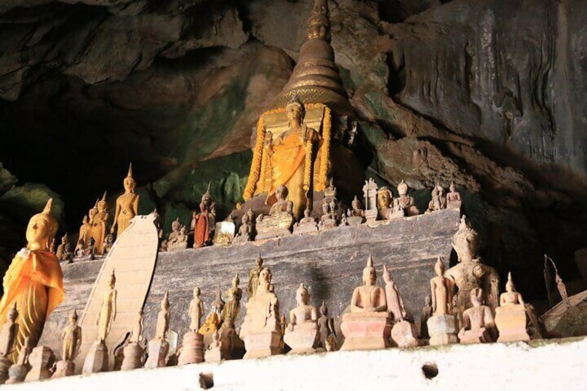 A cave temple with numerous statues and a prominent golden stupa. 5