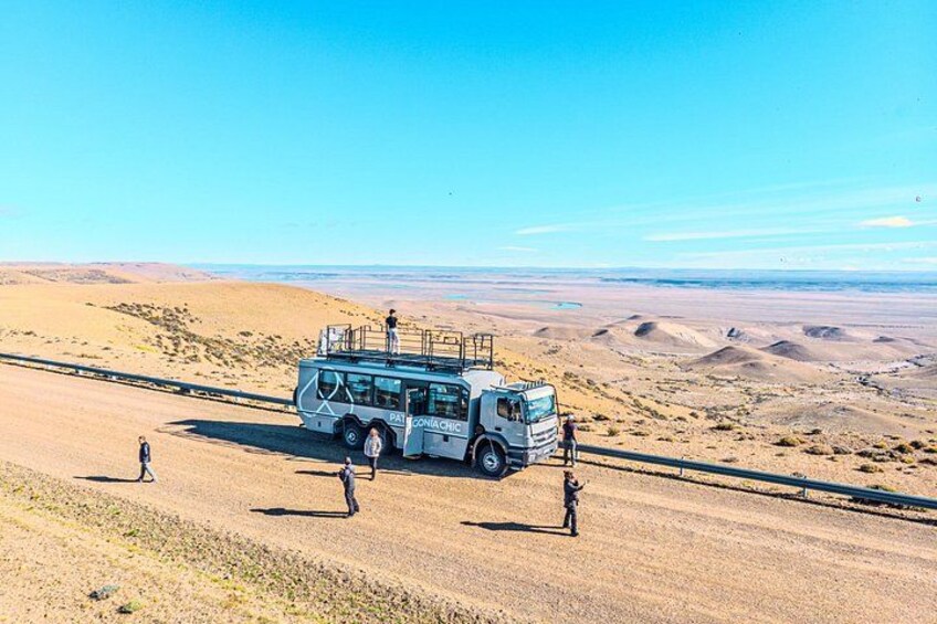 A bus on a desert road with people walking beside it. 2