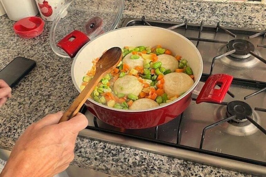 Une personne cuisine sur une cuisinière avec une casserole rouge, une cuillère en bois et un téléphone intelligent posé sur le comptoir. 5