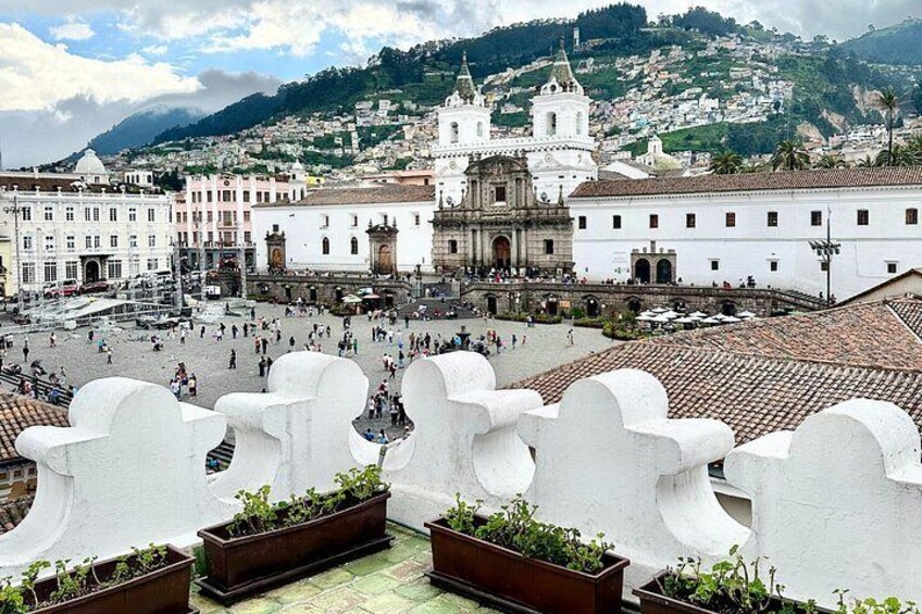 Una plaza con edificios blancos, una iglesia y una colina al fondo. 3