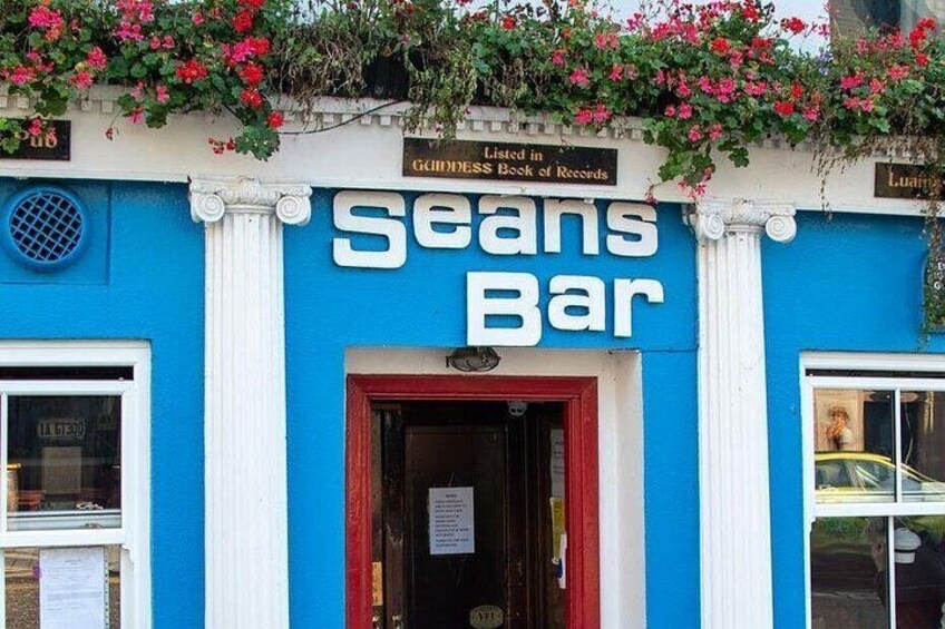 Ein blaues Gebäude mit einer roten Tür und einem Schild, auf dem 'Seans Bar' steht. 2