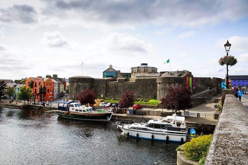 A river with boats, a stone wall, and colorful buildings. 3