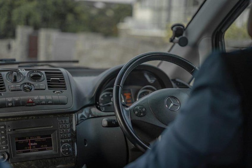 The interior of a car with a steering wheel, dashboard, and infotainment system. 1