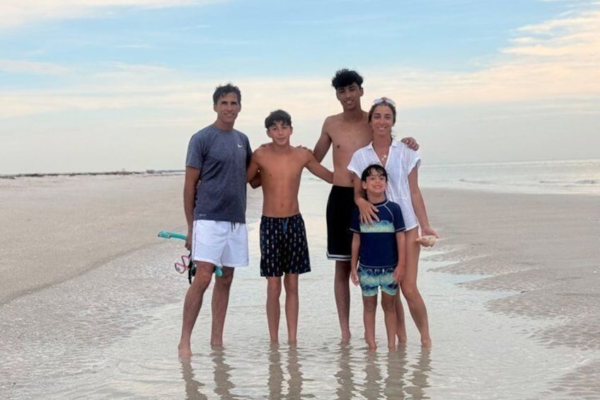 A group of people standing on a beach with the ocean in the background. 2