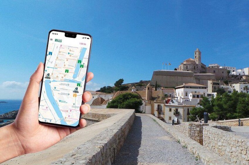 A hand holding a smartphone displaying a map with a coastal town in the background. 1