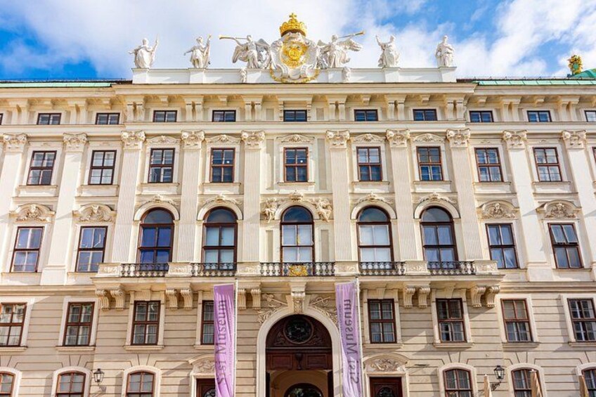 A large, ornate building with multiple windows and statues on the roof. 3