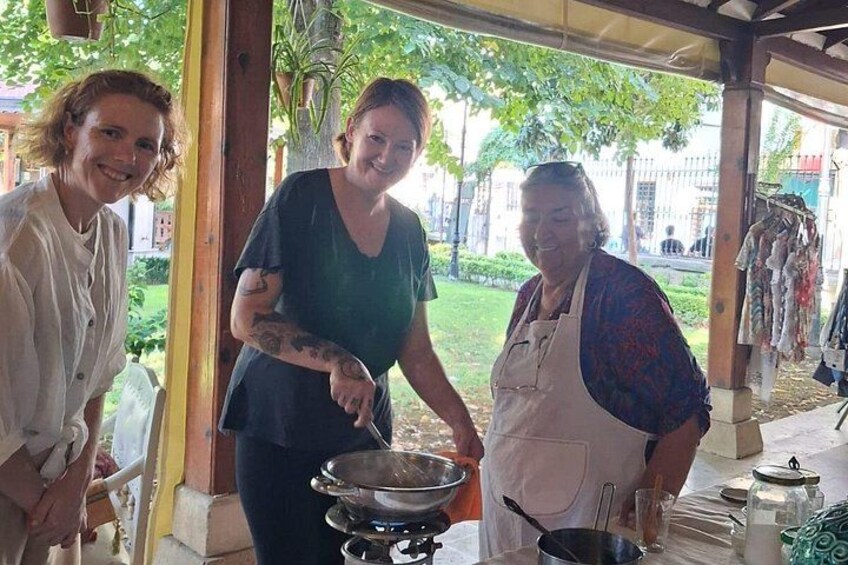 Drie personen koken buiten, onder een overdekte ruimte, met een barbecue en kookgerei. 5