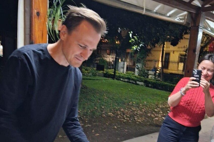 Un hombre con una camisa oscura y una mujer con un suéter rojo tomando una fotografía. 2