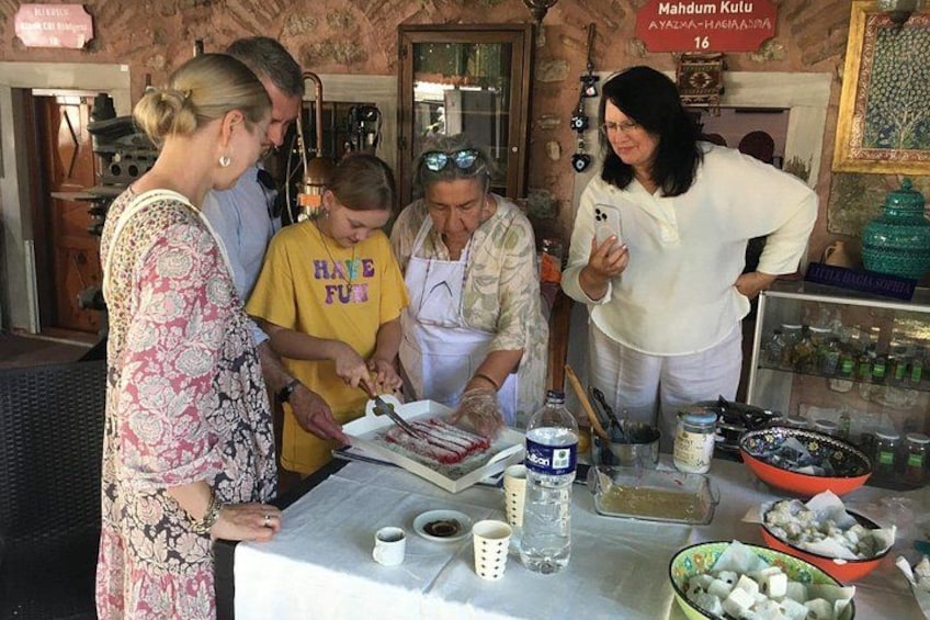 A group of people preparing food at a table with various ingredients and utensils. 2
