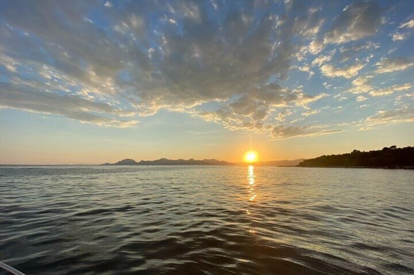 Un atardecer sobre aguas tranquilas, con una costa lejana y montañas al fondo. 1