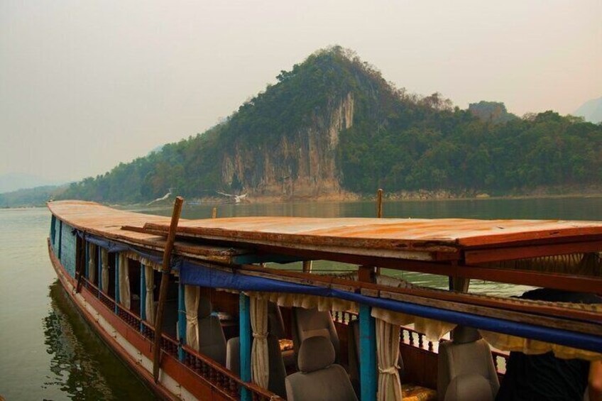 A boat docked at a pier with a forested mountain in the background. 5