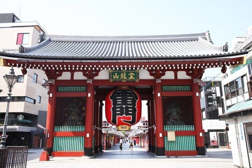 Un torii japonés tradicional, con una estructura grande de color rojo y verde, un farol de piedra y un cielo despejado. 5