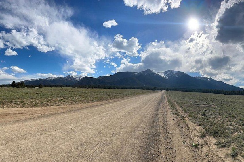 A dirt road leading to a mountain range under a partly cloudy sky. 2