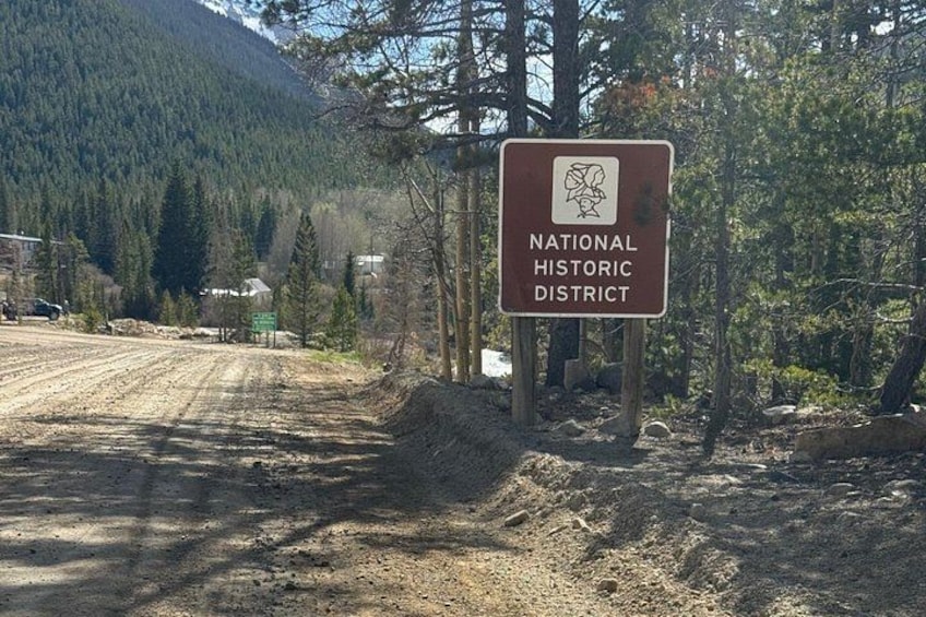 A sign for the National Historic District with a forested mountain background. 4