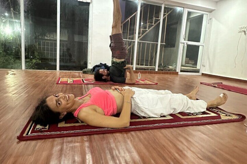 Two people practicing yoga on mats in a room with wooden flooring and large windows. 3