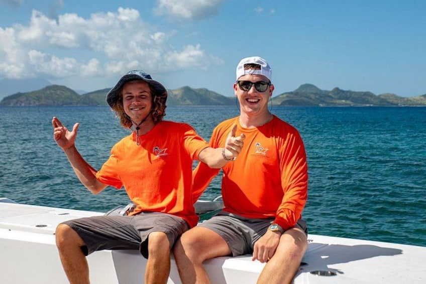 Dos personas en un bote, con un mar azul cristalino e islas distantes al fondo. 2