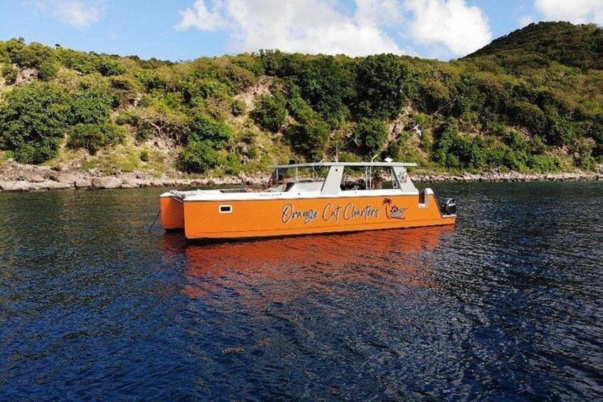 A boat named 'Orange Cat Charters' on a calm body of water with a hilly landscape in the background. 1