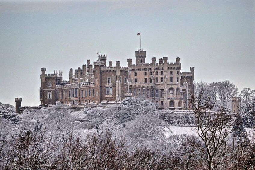 A large, historic building with multiple towers and turrets, surrounded by snow-covered trees. 3