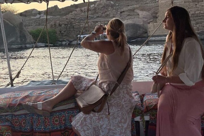 Two women on a boat with a rocky shoreline in the background. 5