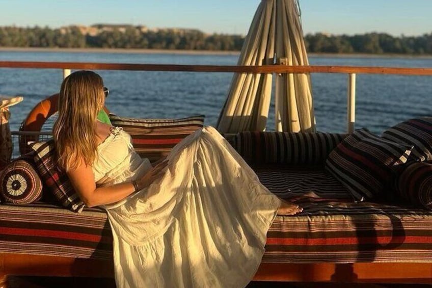 A person relaxing on a boat with striped cushions and a canopy. 1