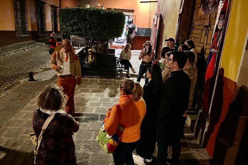 A group of people gathered outside a building with a tree and steps leading up to it. 3